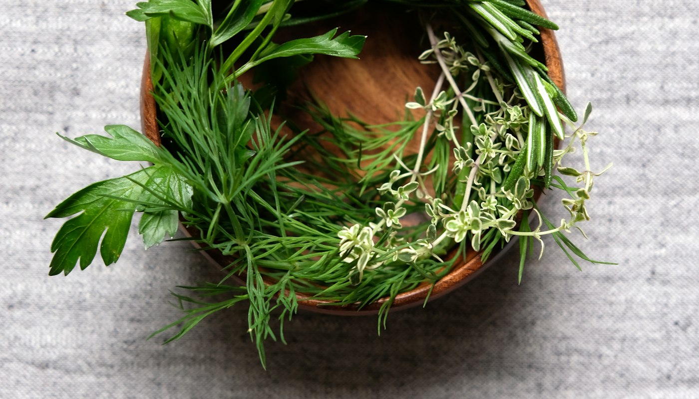 Fresh herbs gathered in a wooden bowl before milling and extraction