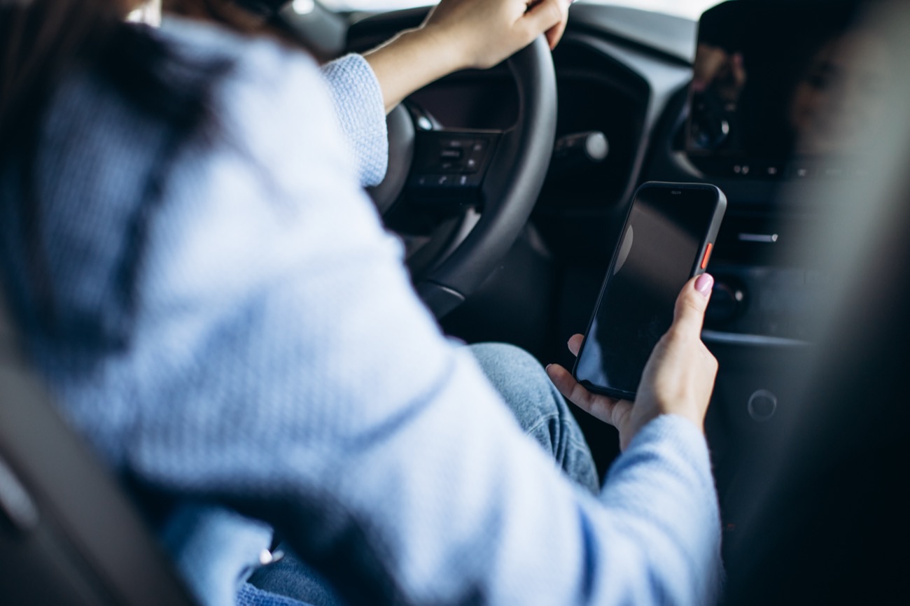 Fahrer greift während der Fahrt zum Smartphone