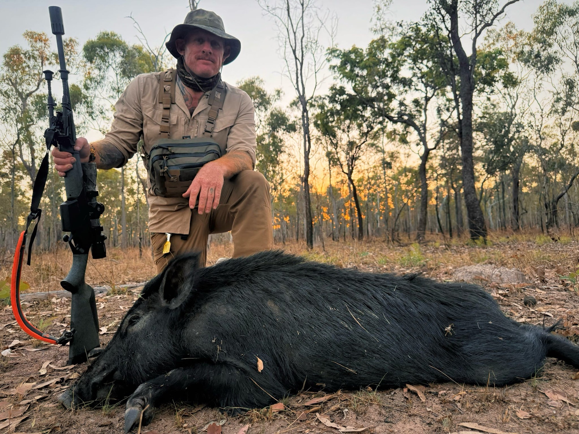 A hunter with a wild boar taken in the late afternoon