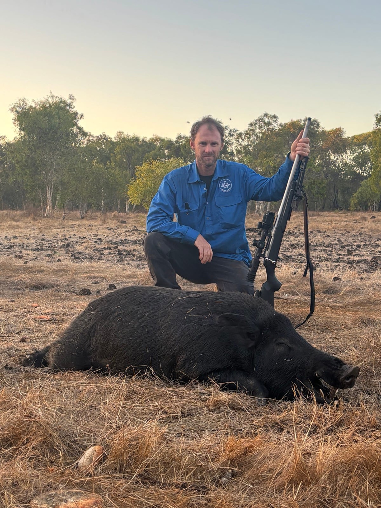 A hunter kneeling with a wild boar taken at first light