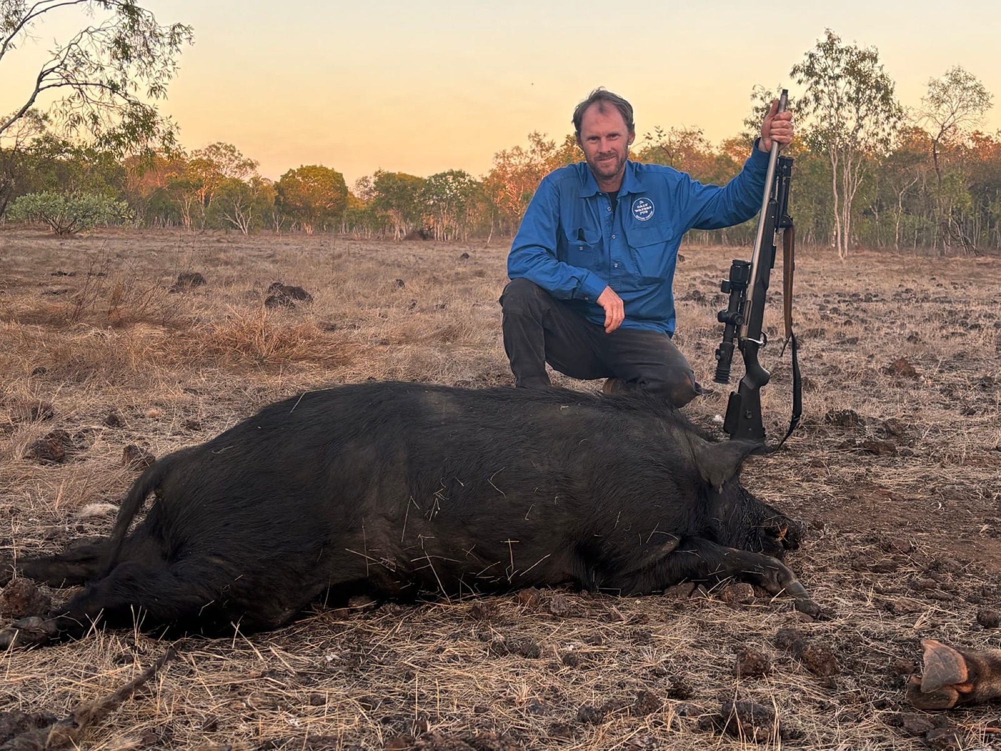 A hunter standing with a wild boar taken at last light