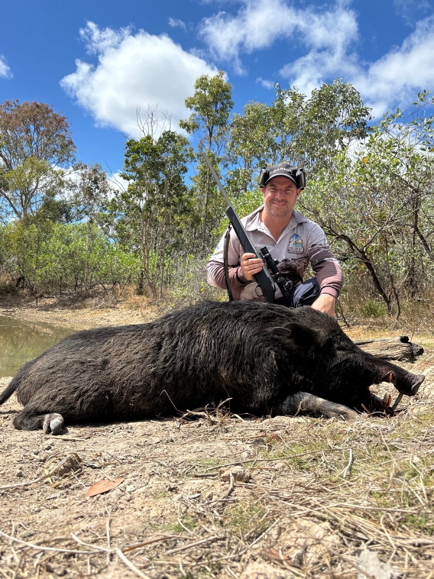 A hunter with a wild boar under a clear sky