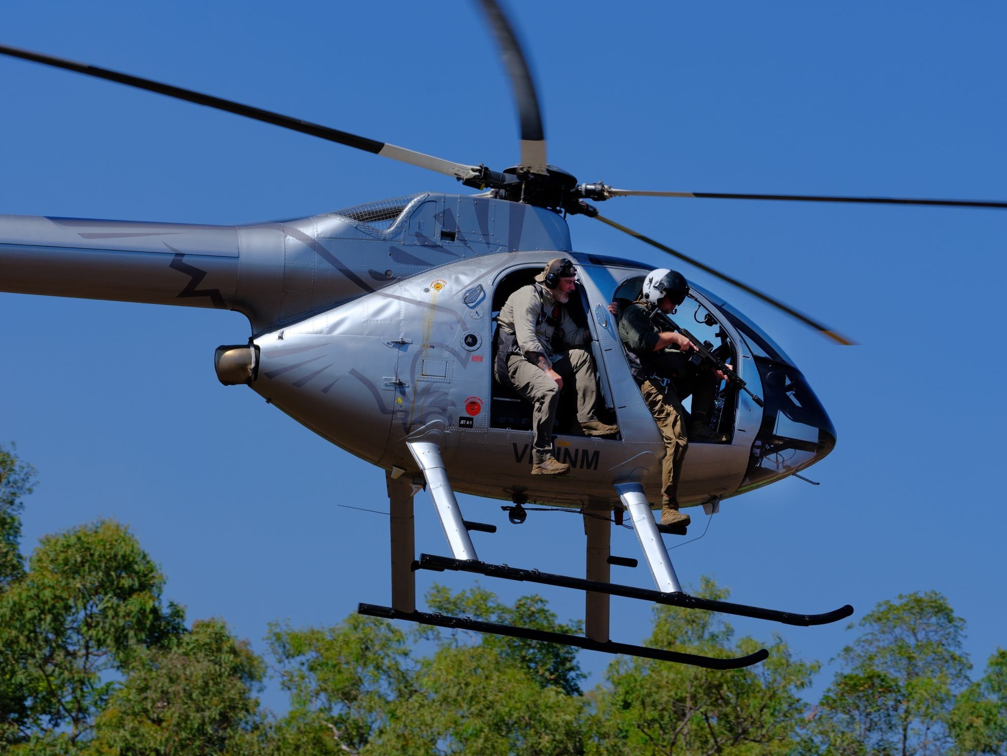 A helicopter flying low over the trees with hunters aboard