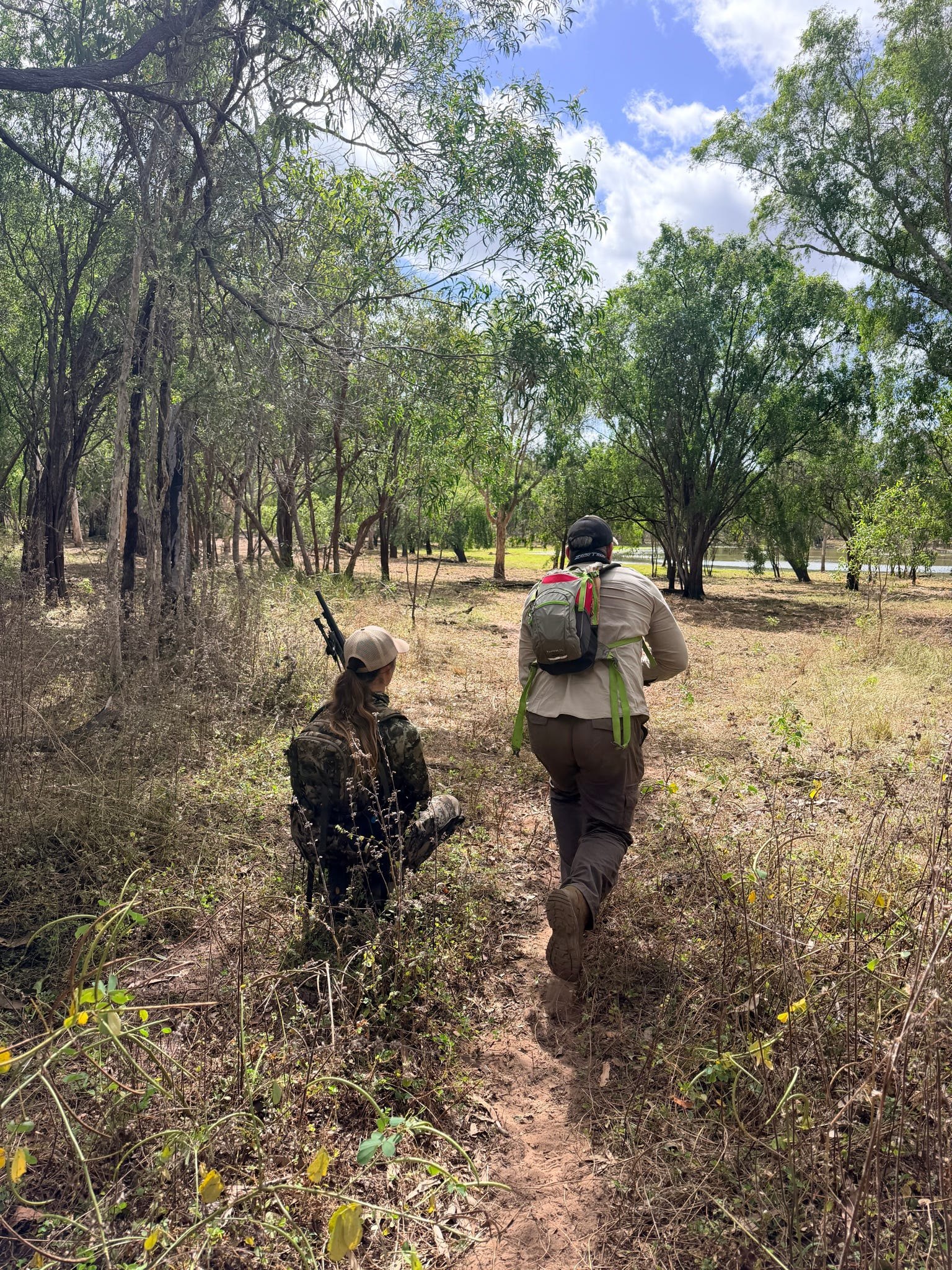 Two hunters walking a track through long grass and open forest
