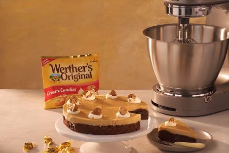 Dessert with caramel topping beside Werther's Original candies and a silver stand mixer on a counter.
