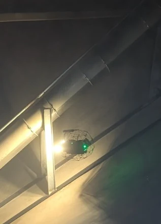 Elios 3 leuchtet in einem dunklen Silo eine Förderleitung an der Wand aus