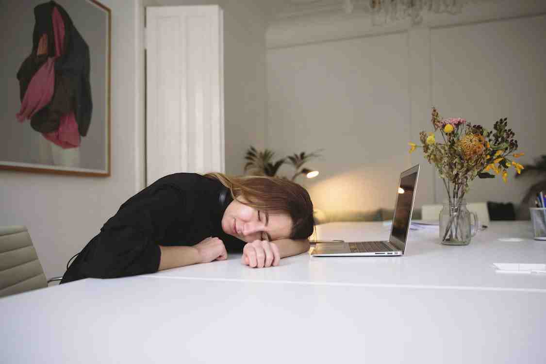 A burned-out office worker resting their head on their desk.