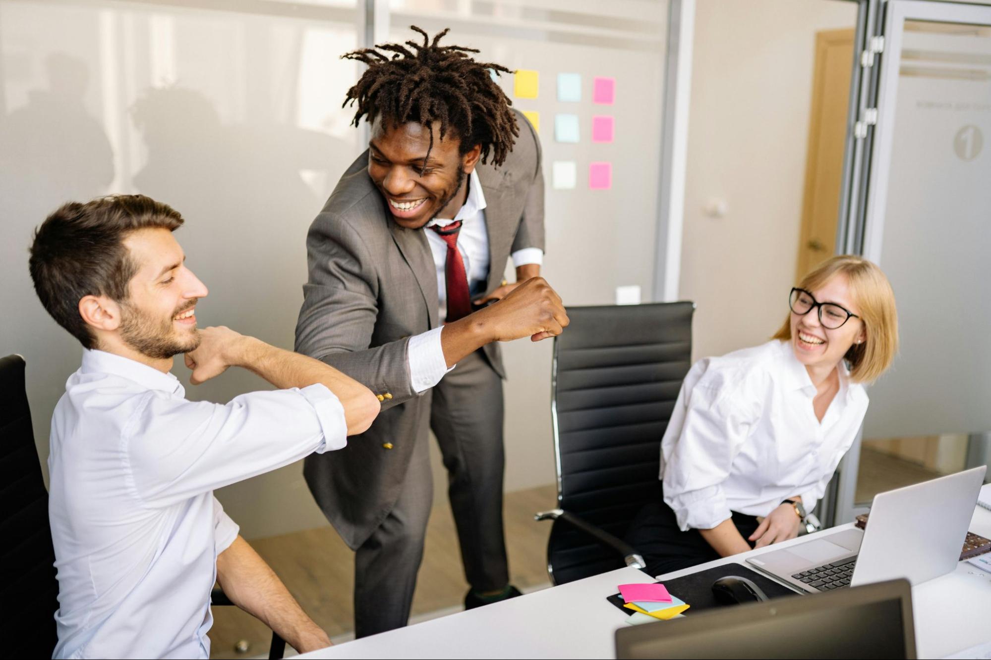Three employees celebrating in an office setting. 