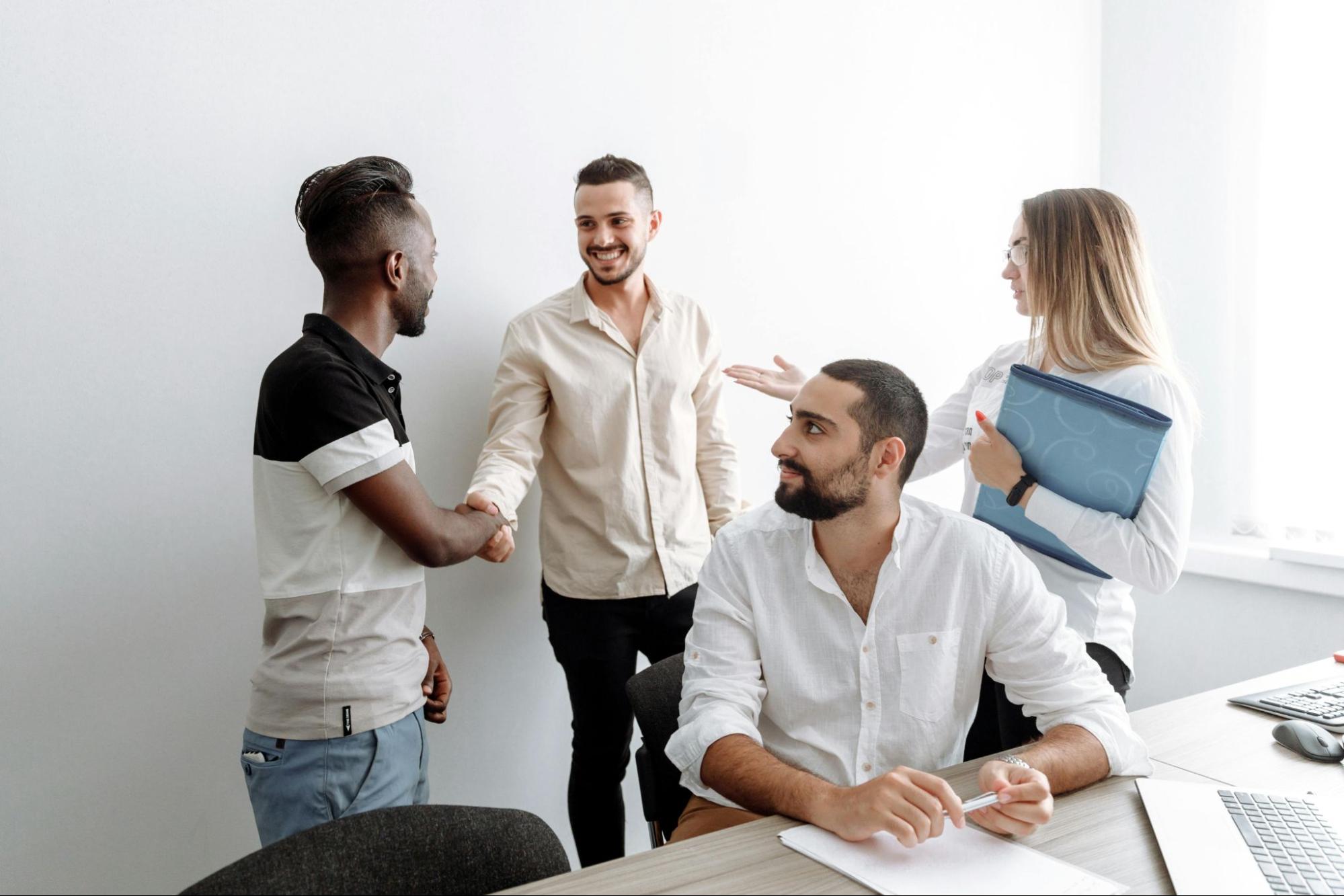 A team of four employees having a conversation in an office setting.