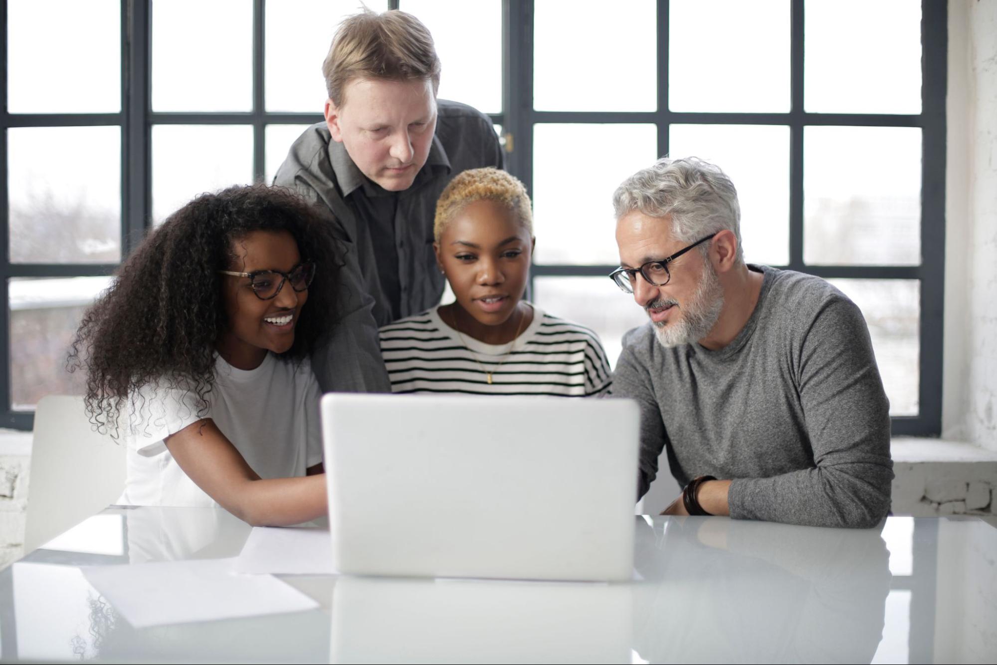 A diverse group of people using a laptop in a modern office.