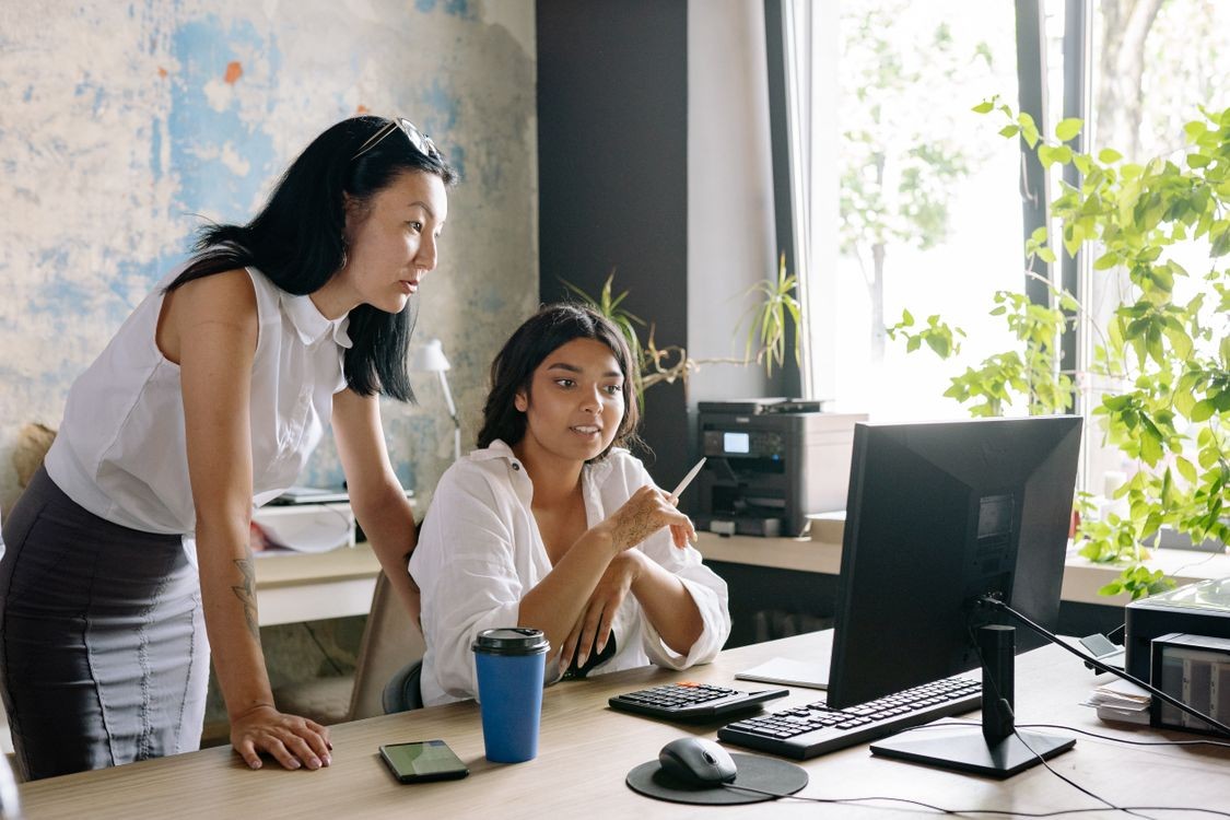 Two people viewing and discussing something displayed on a computer monitor in an office.