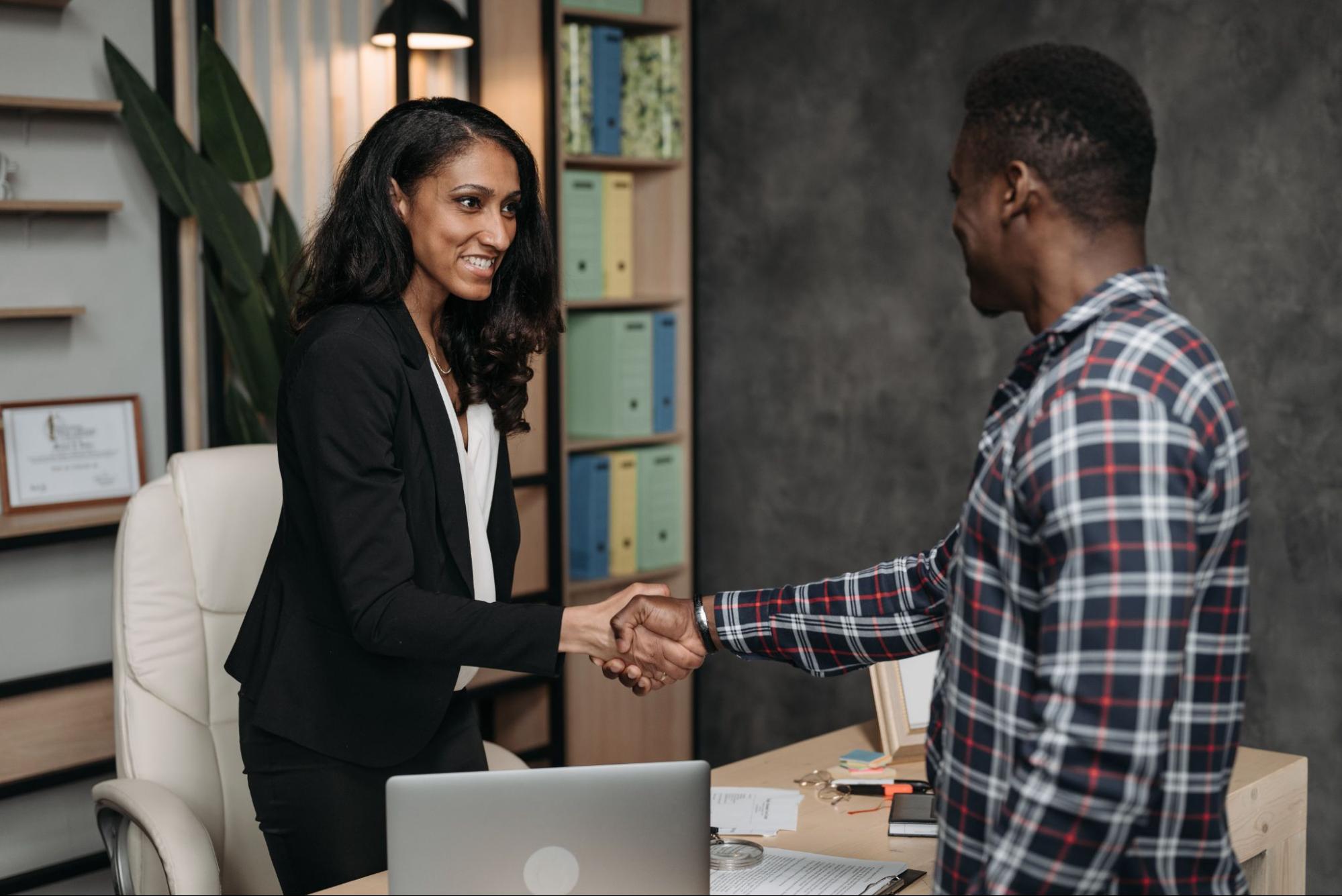 Two people shaking hands in an office setting.