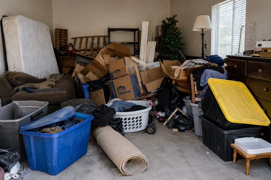 Room filled with a mattress, sofa, boxes and storage totes before a rental turnover clear-out