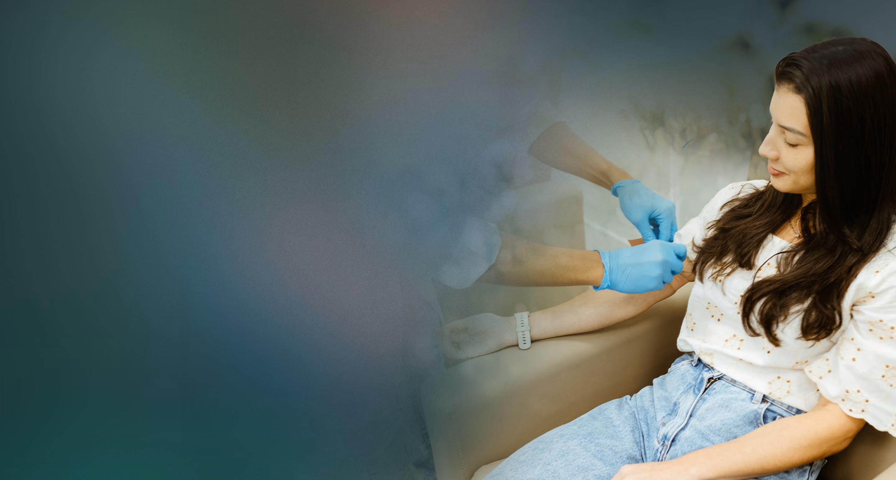 Woman sitting while a healthcare professional with blue gloves prepares to draw blood from her arm.