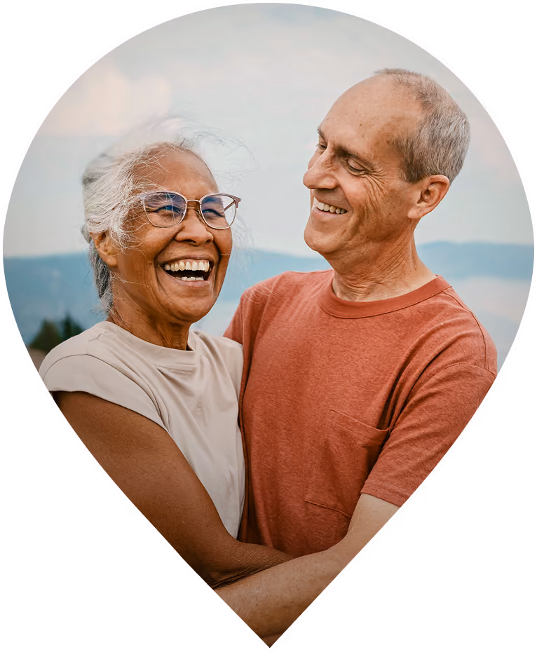 Smiling older couple embracing outdoors with mountains in the background