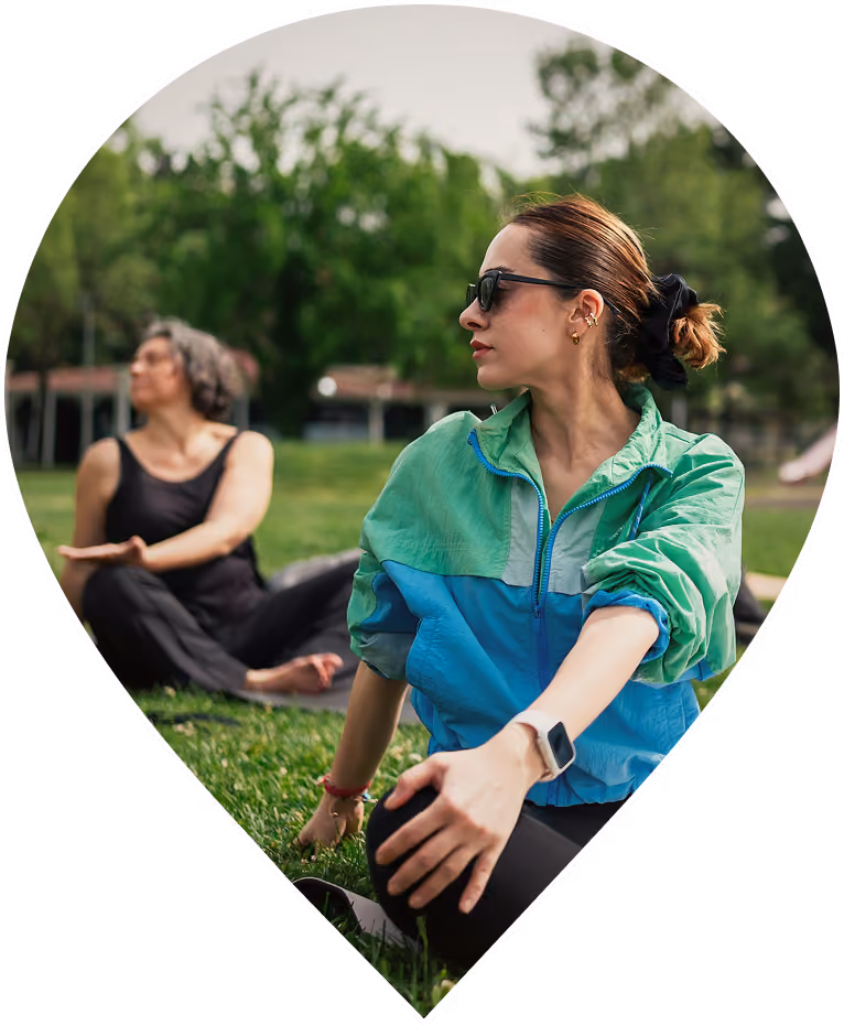 Woman stretching outdoors during a group exercise session in the park