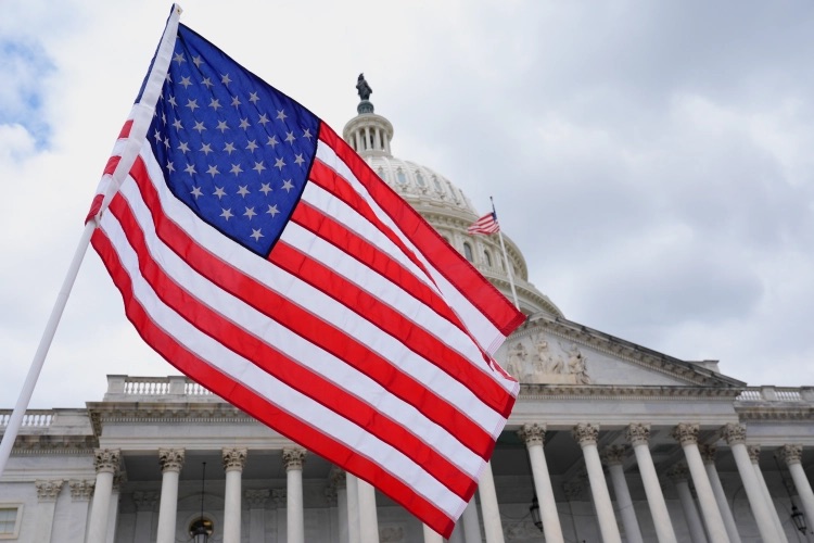 American flag waving in front of the U.S. Capitol building.