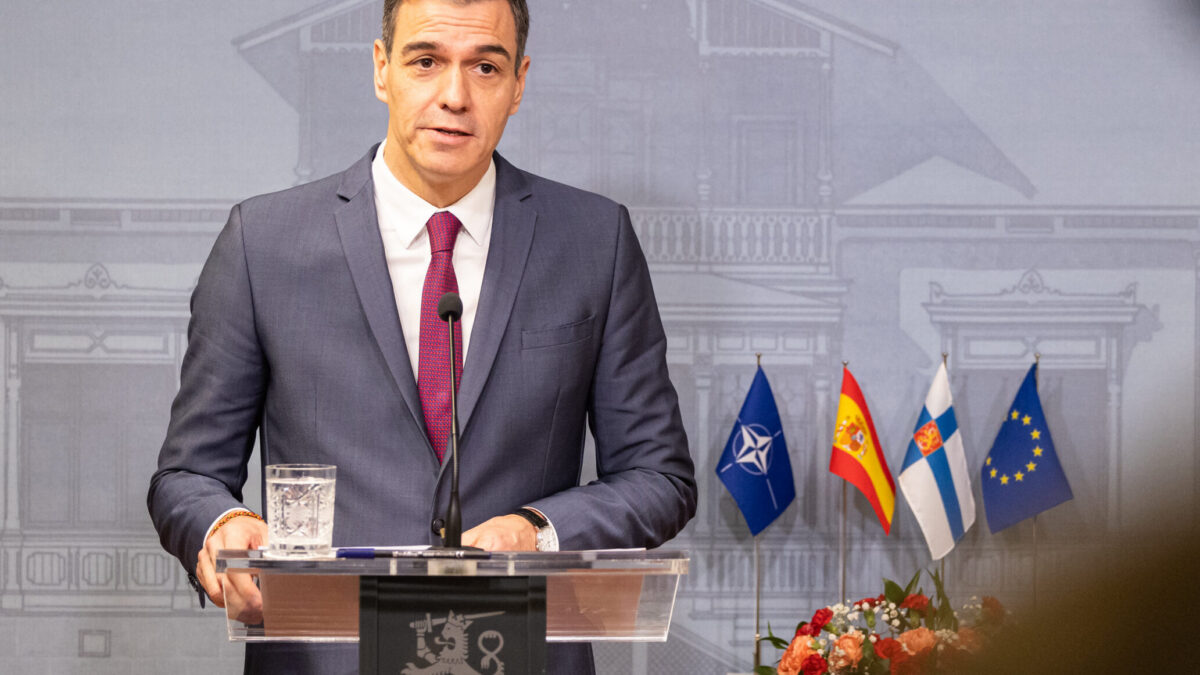 Spanish Prime Minister Pedro Sánchez speaking at a podium with NATO, Spain, Finland, and European Union flags behind him.