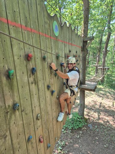 Colleague climbing a bouldering wall in the woods