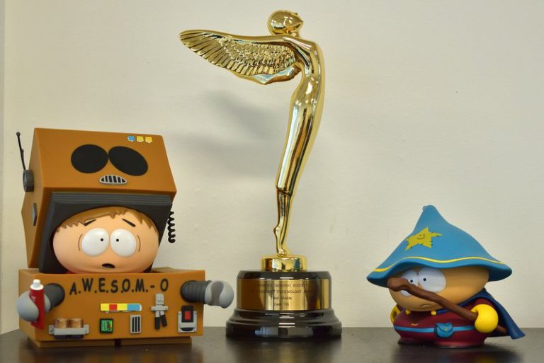 Award statuette on a shelf between two cartoon figurines