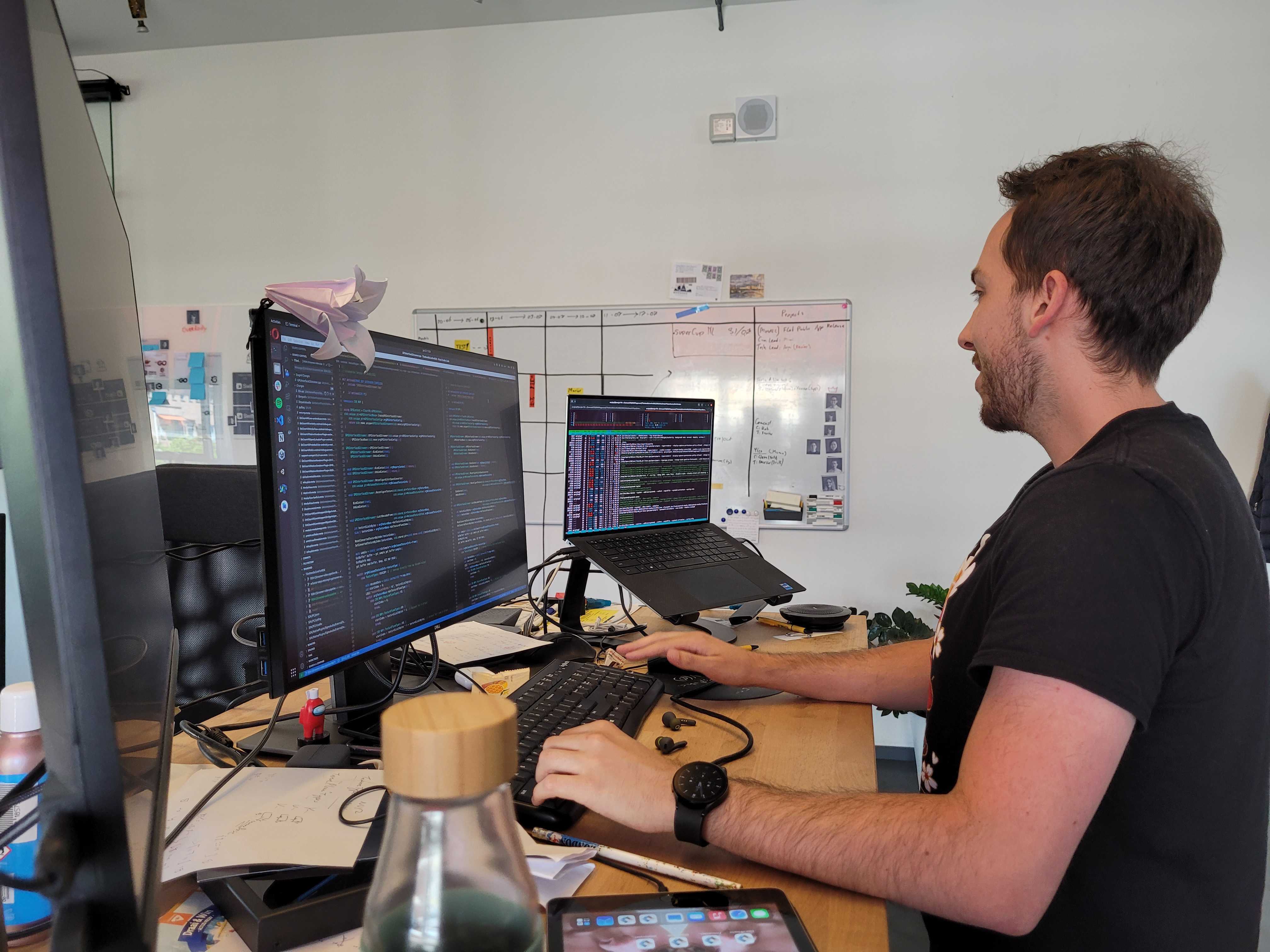 Developer working at a desk with two monitors of code