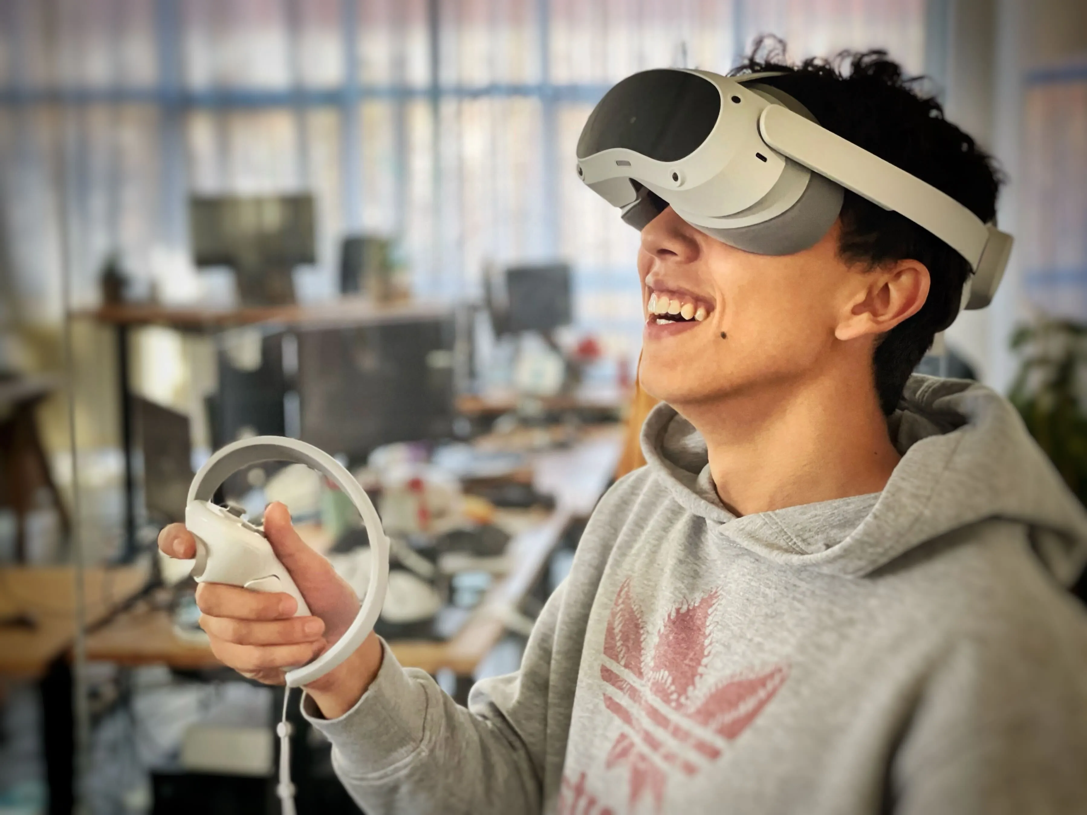 Person smiling while using a Pico VR headset and controller in an office