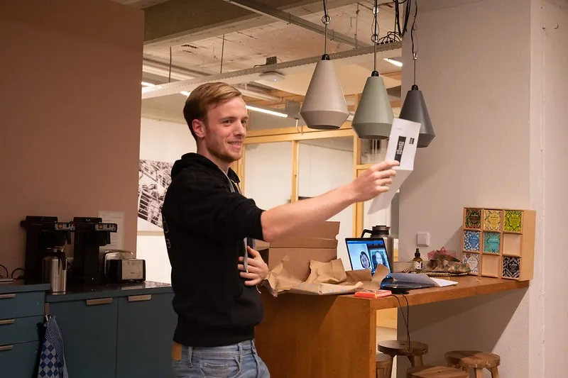 Colleague holding up a Sinterklaas present, laptop with a video call beside him