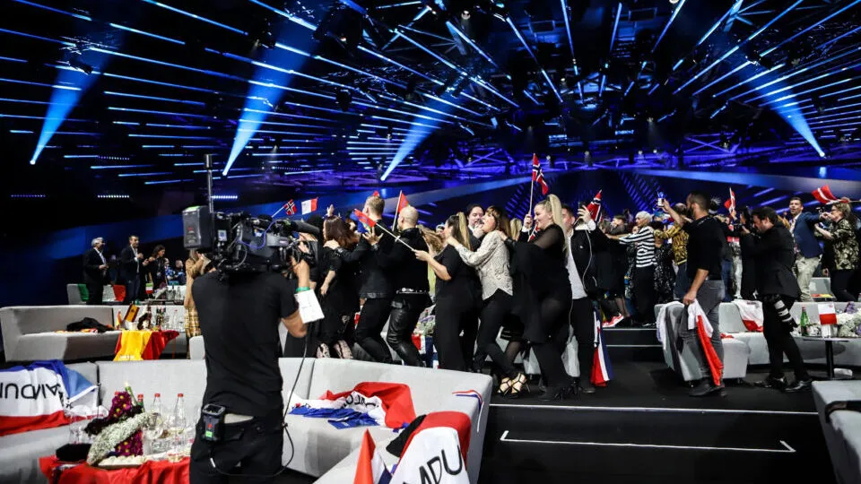 Crowd celebrating at an event with camera crews in front