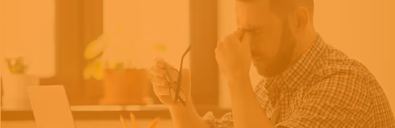 Stressed man rubbing his eyes at a desk
