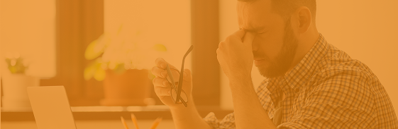 Stressed man rubbing his eyes at a desk