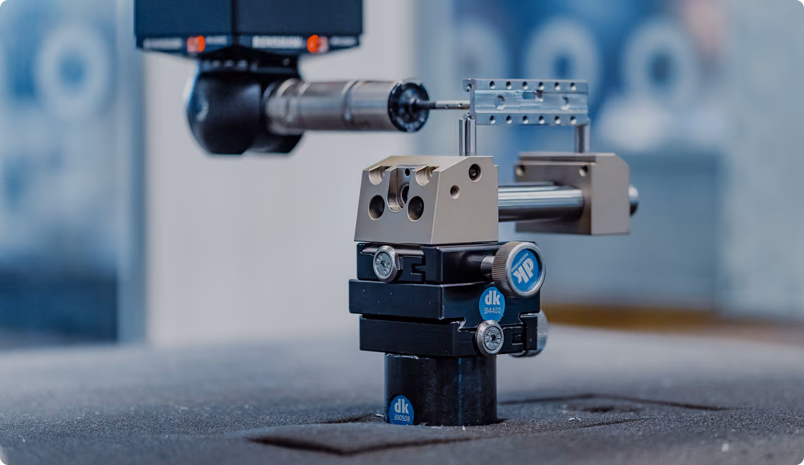 Präzises mechanisches Messgerät mit Metallstange und Justierschrauben auf grauer Oberfläche.