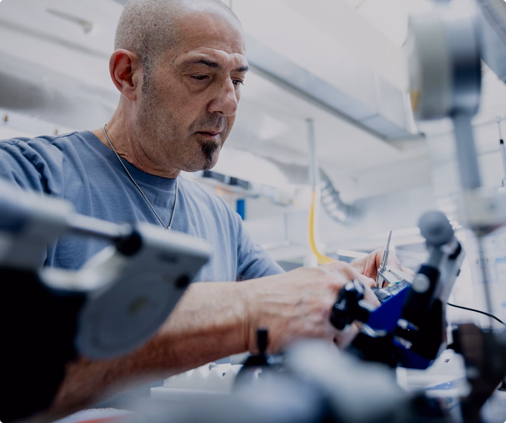 Ein Mann arbeitet konzentriert an einem mechanischen Gerät in einer Werkstatt.