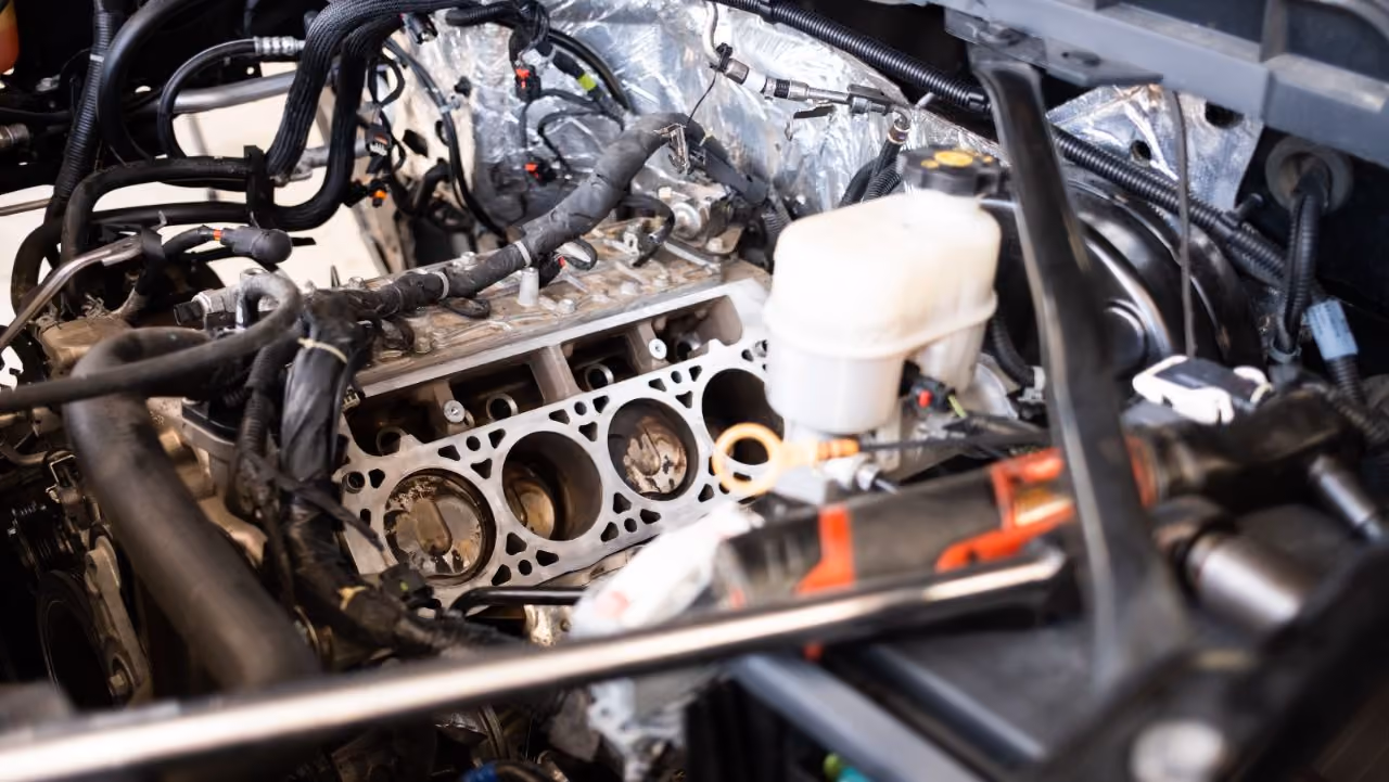 A close-up view of an open engine bay showing exposed engine cylinders with the cylinder head removed during a major repair.