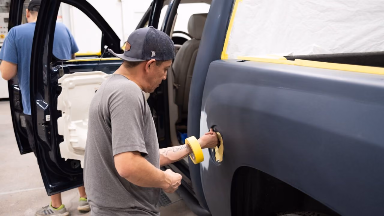 Technician buffing a refinished panel during paint work