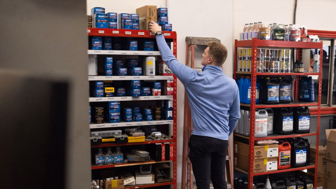 Technician pulling fluids from the parts shelving in the service department