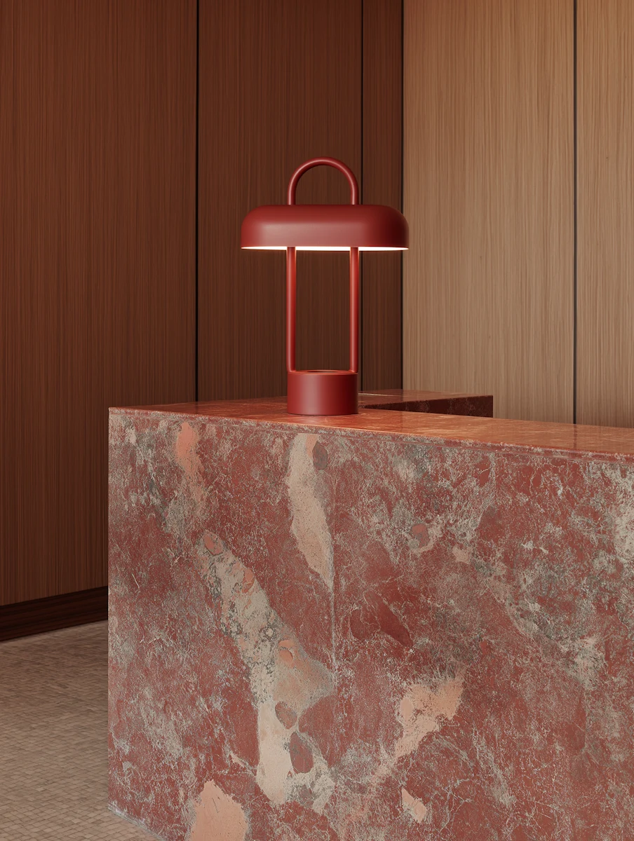 Modern red lantern-style lamp on a red and beige marble countertop against a wooden paneled wall.
