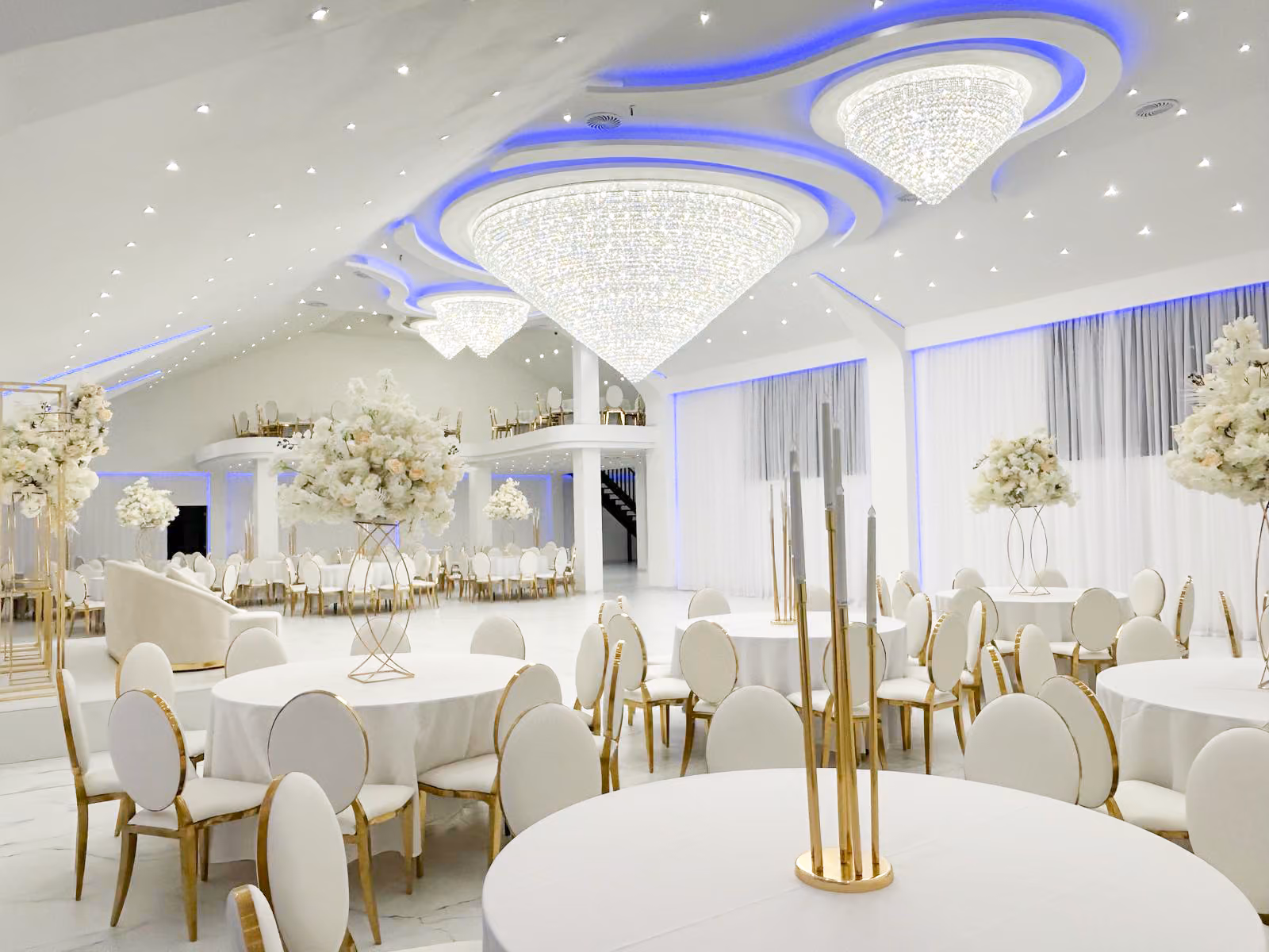 Feestzaal met witte tafels en moderne blauwe verlichting
