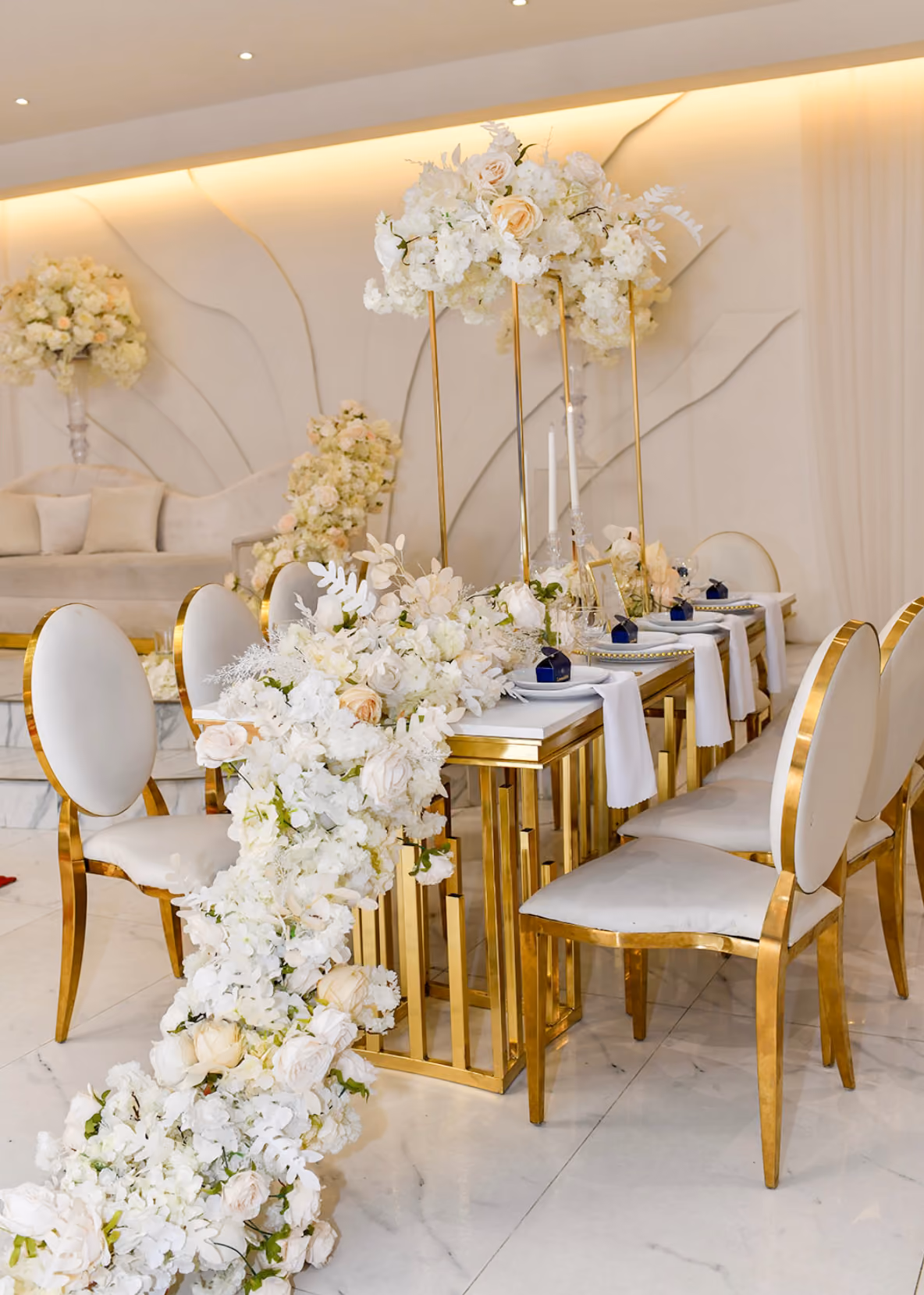 Luxe gedekte feesttafel met witte bloemen en gouden stoelen