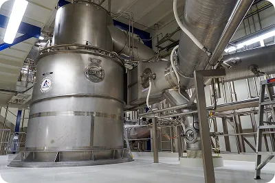 Large industrial stainless steel machinery and pipes in a clean factory setting.
