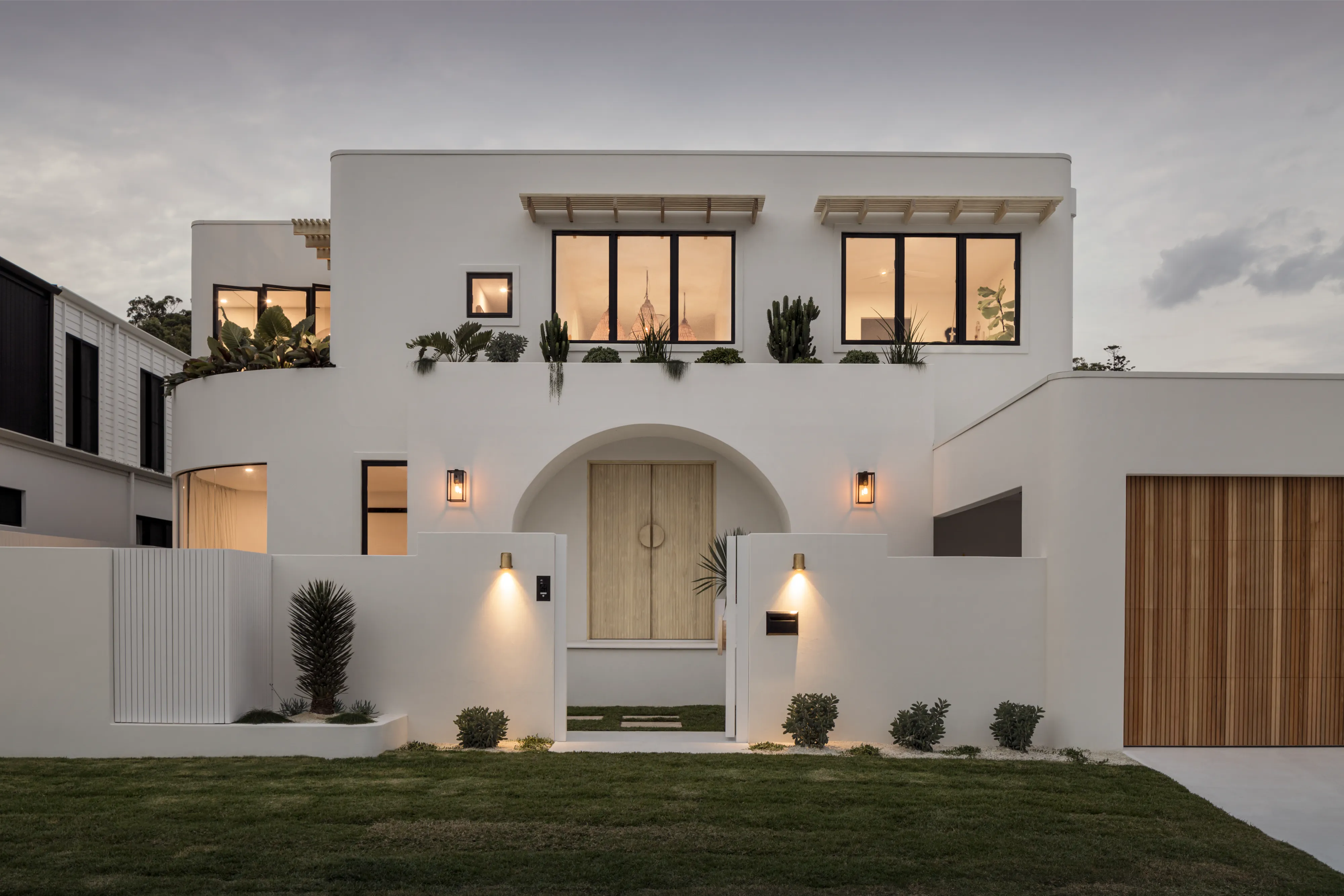 Contemporary white coastal home with an arched entrance and timber garage door on the Gold Coast