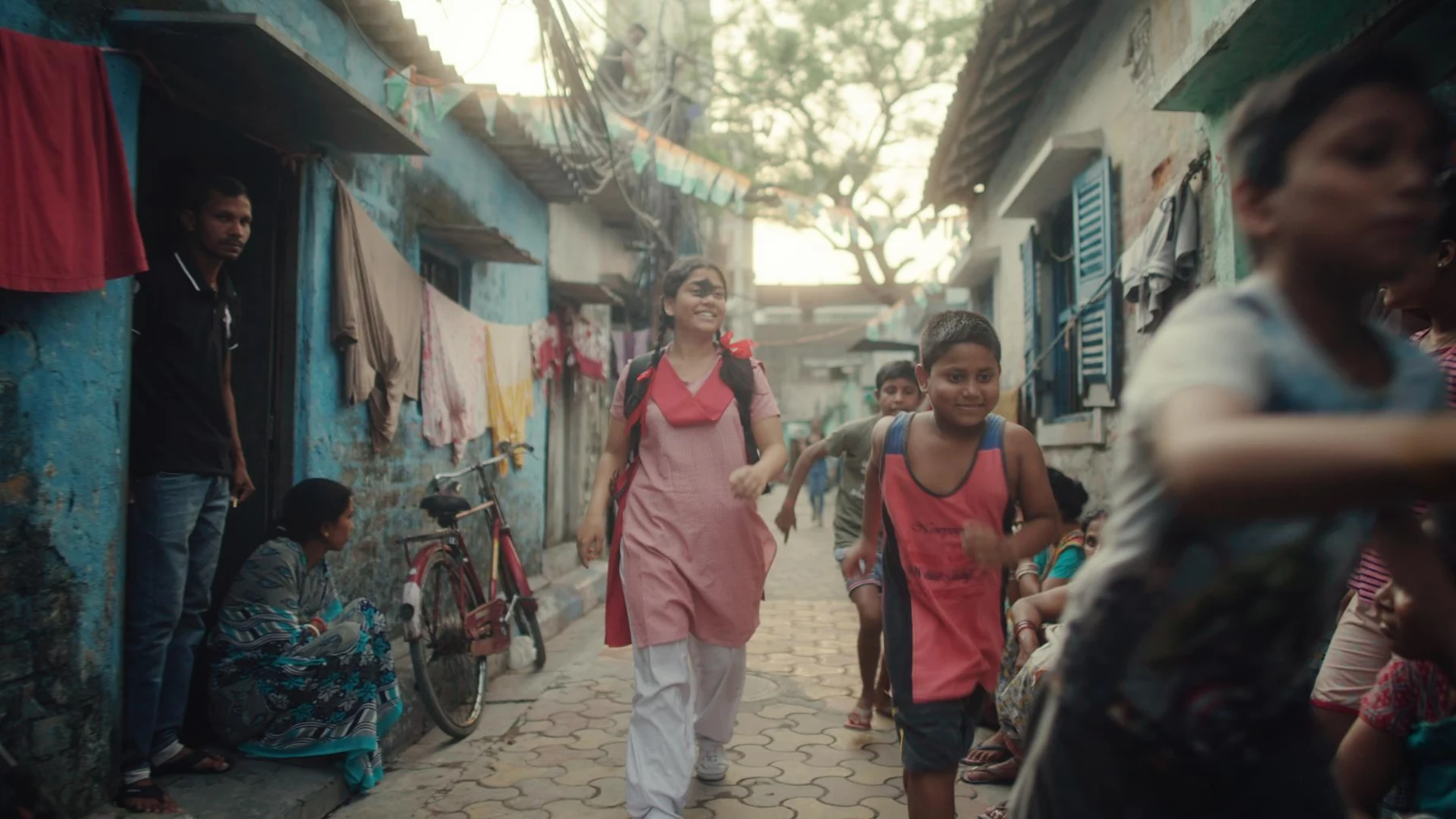 Kali — Two girls walk through a lively neighbourhood lane