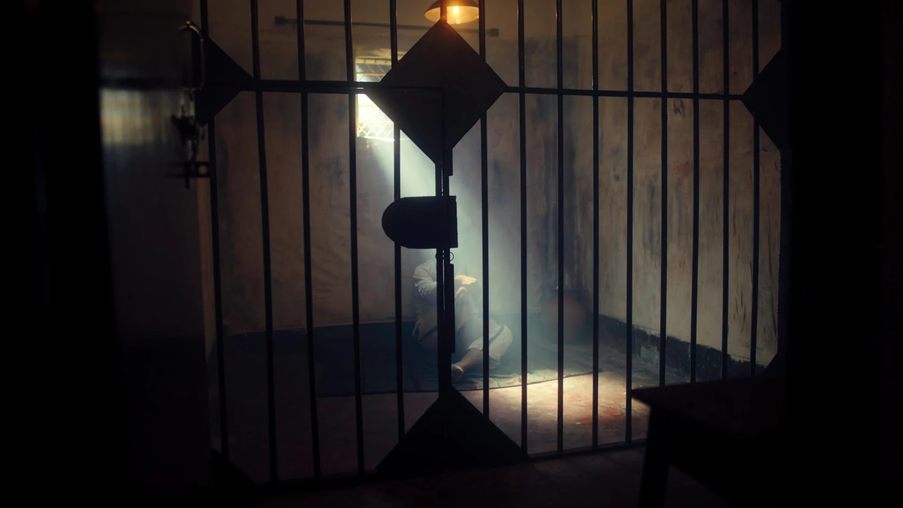 Kali — A silhouette behind jail bars in a shaft of light