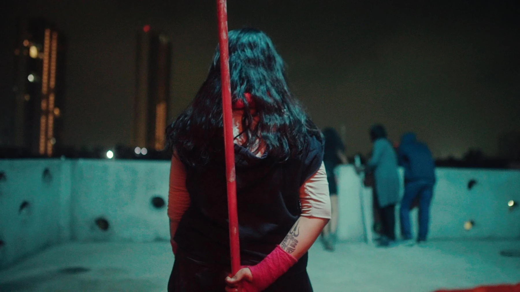 Kali — The vigilante on a rooftop against teal and red light