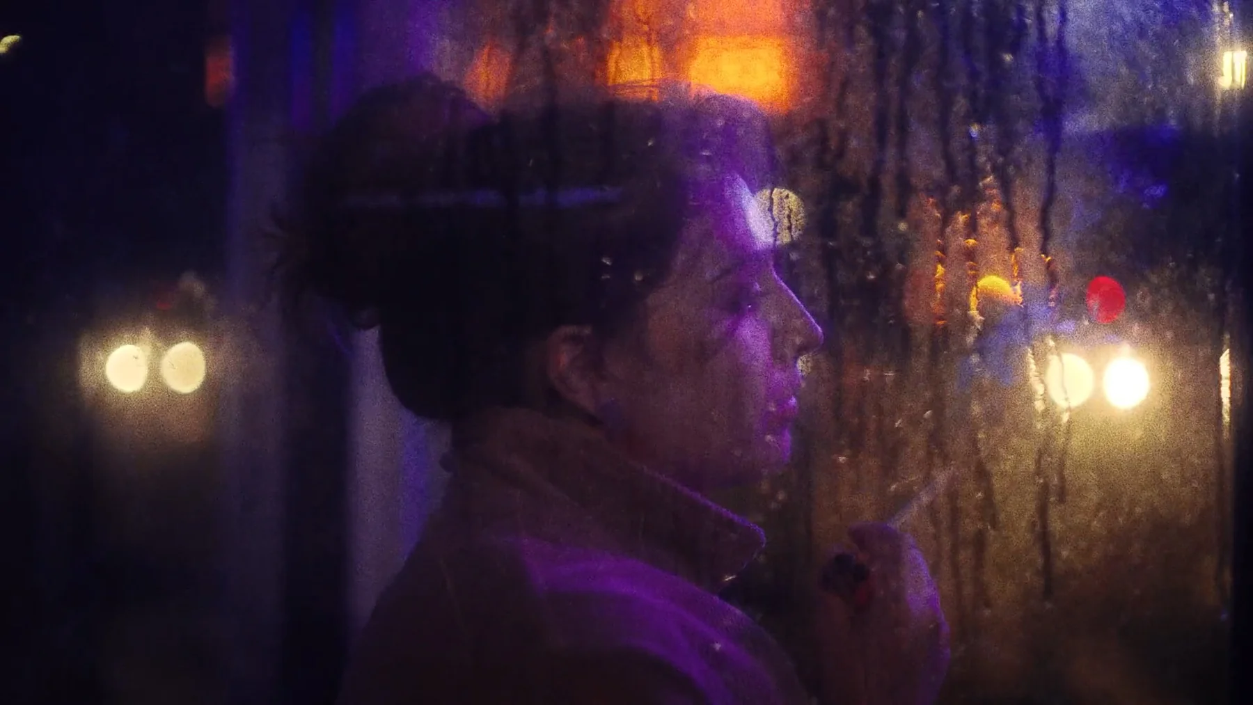 Trust Me — A woman in profile behind rain-streaked glass and violet light