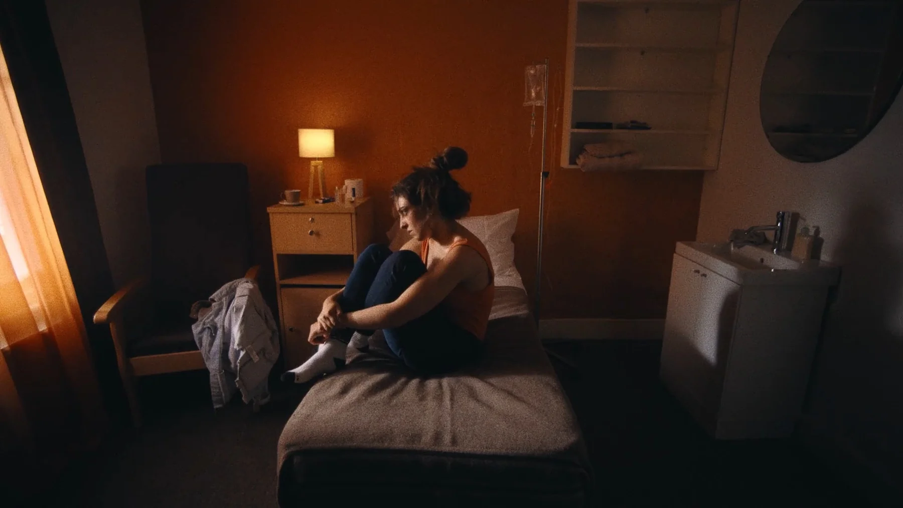 Trust Me — Anne sits curled on a bed in a sunlit hospital room