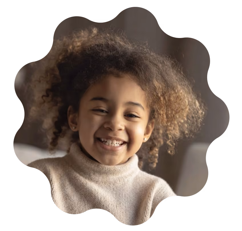 Smiling young girl with curly hair wearing a beige turtleneck sweater.