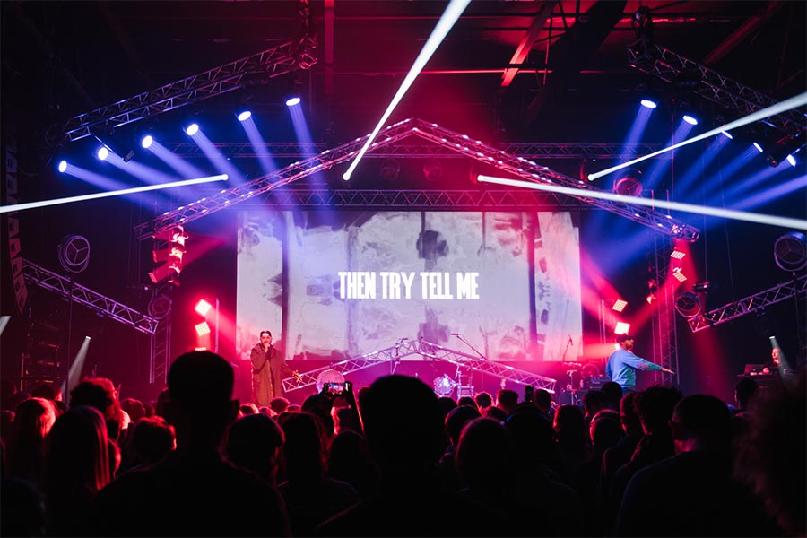 A live performance with dynamic and colourful stage lights on an overhead rig