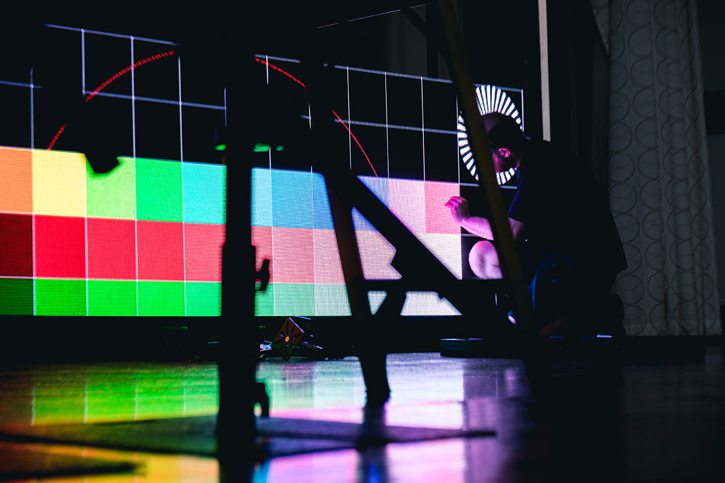 An MTS Live team member working in front of a large colourful LED screen array.