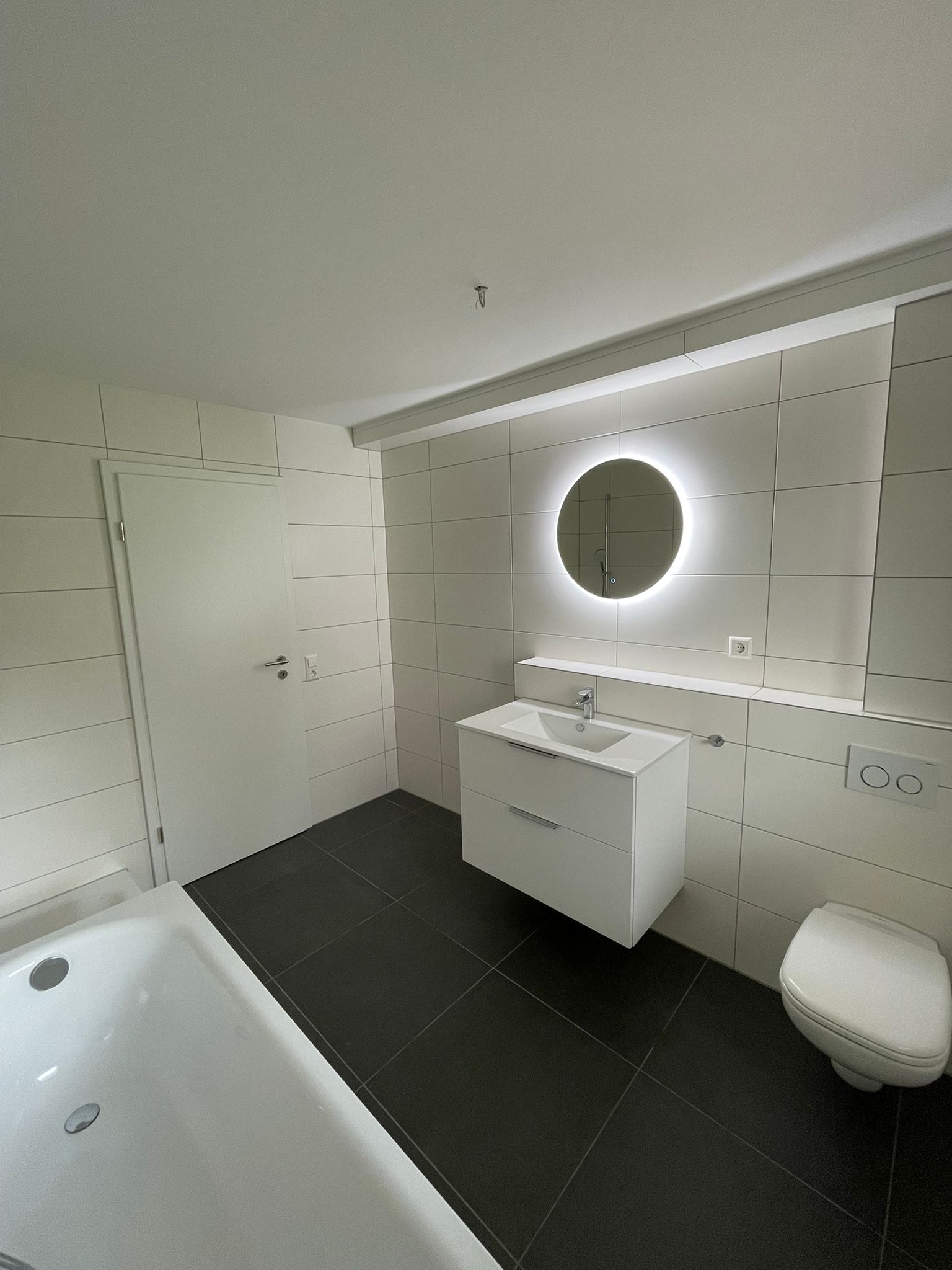 Bad mit Badewanne, Waschtisch und beleuchtetem Spiegel
