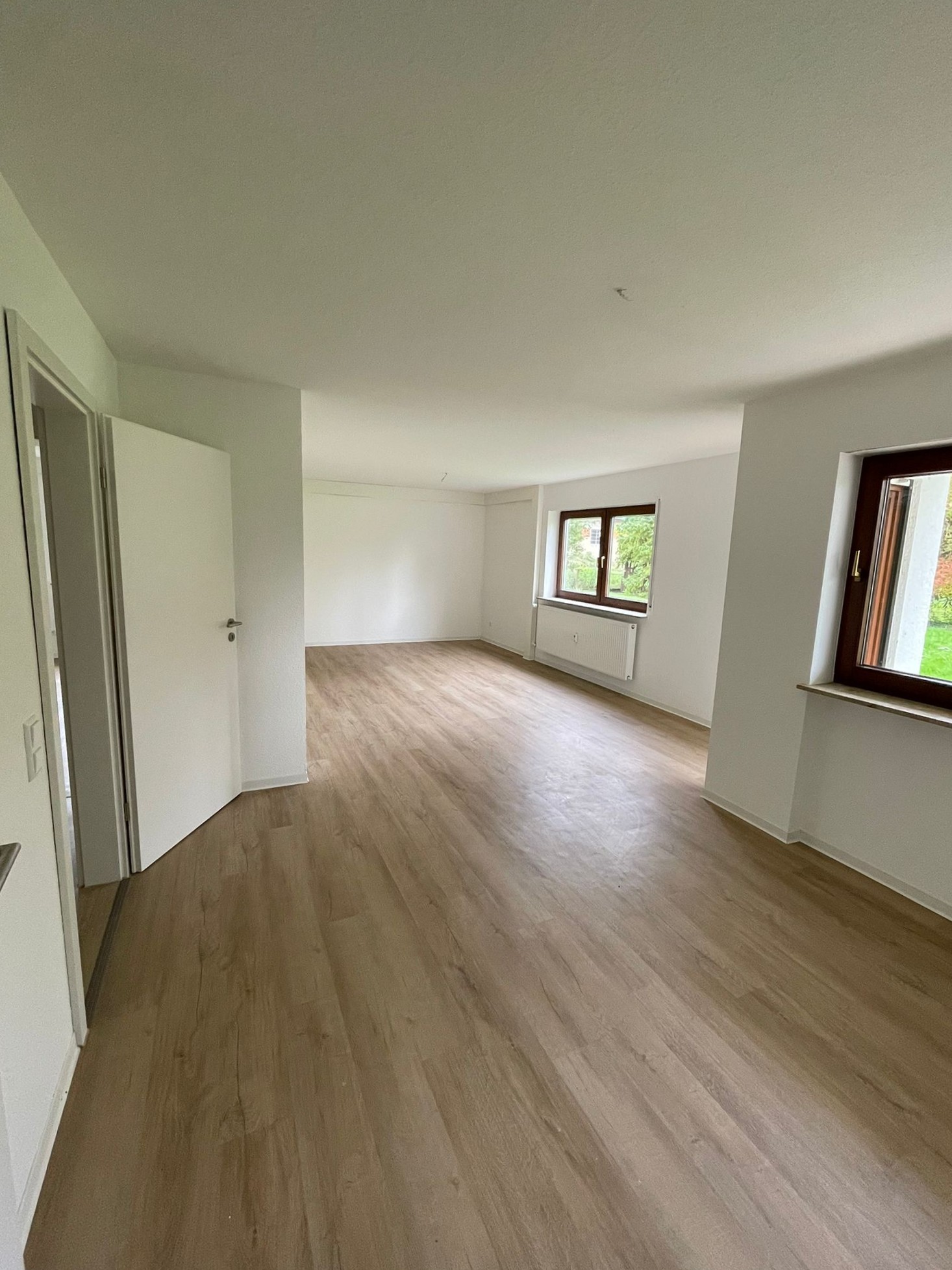 Wohn- und Essbereich mit Vinylboden und Fenstern zum Garten